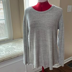 Gray sweater with ribbing down the arms and slightly lower in back.